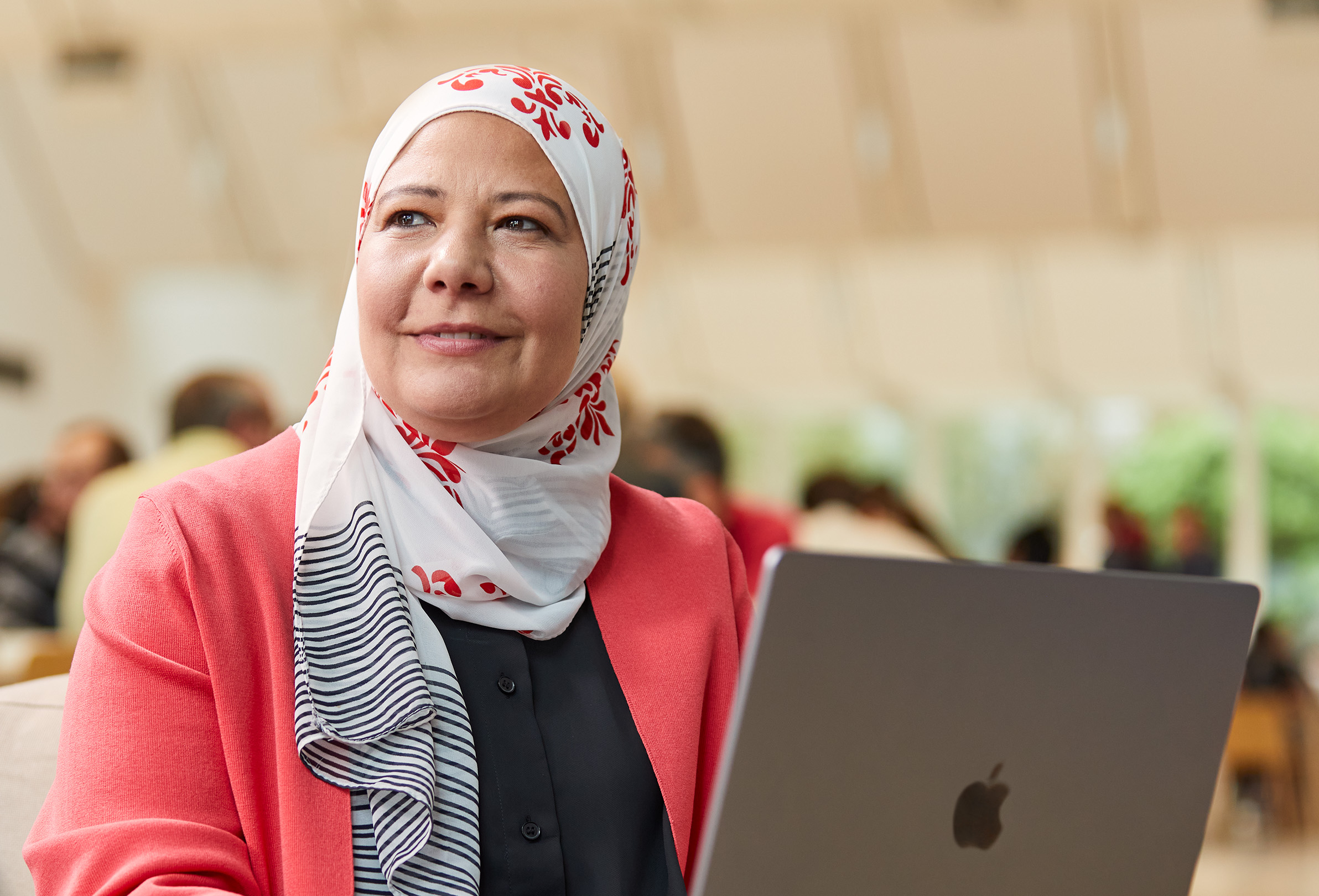 Siedząca i patrząca w lewo pracownica Apple, która zajmuje się czymś na MacBooku.